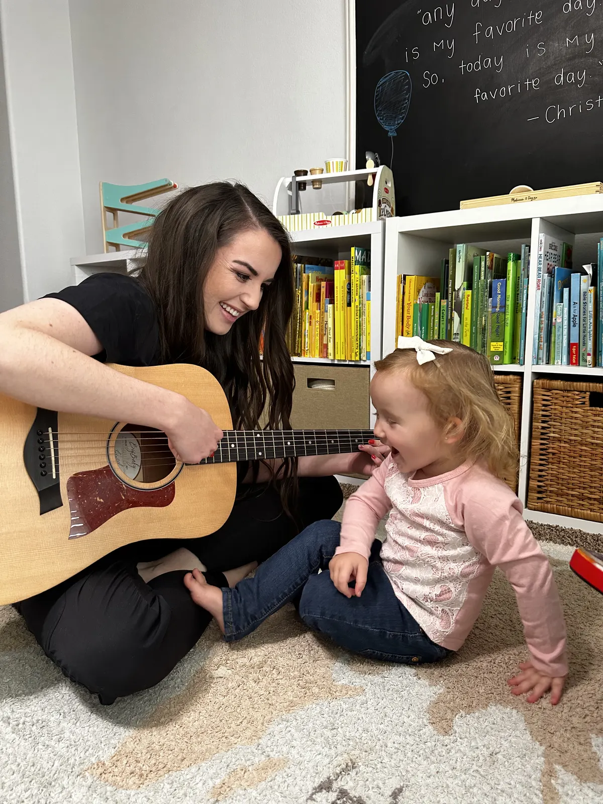 A music therapist playing acoustic guitar with a young child during a session