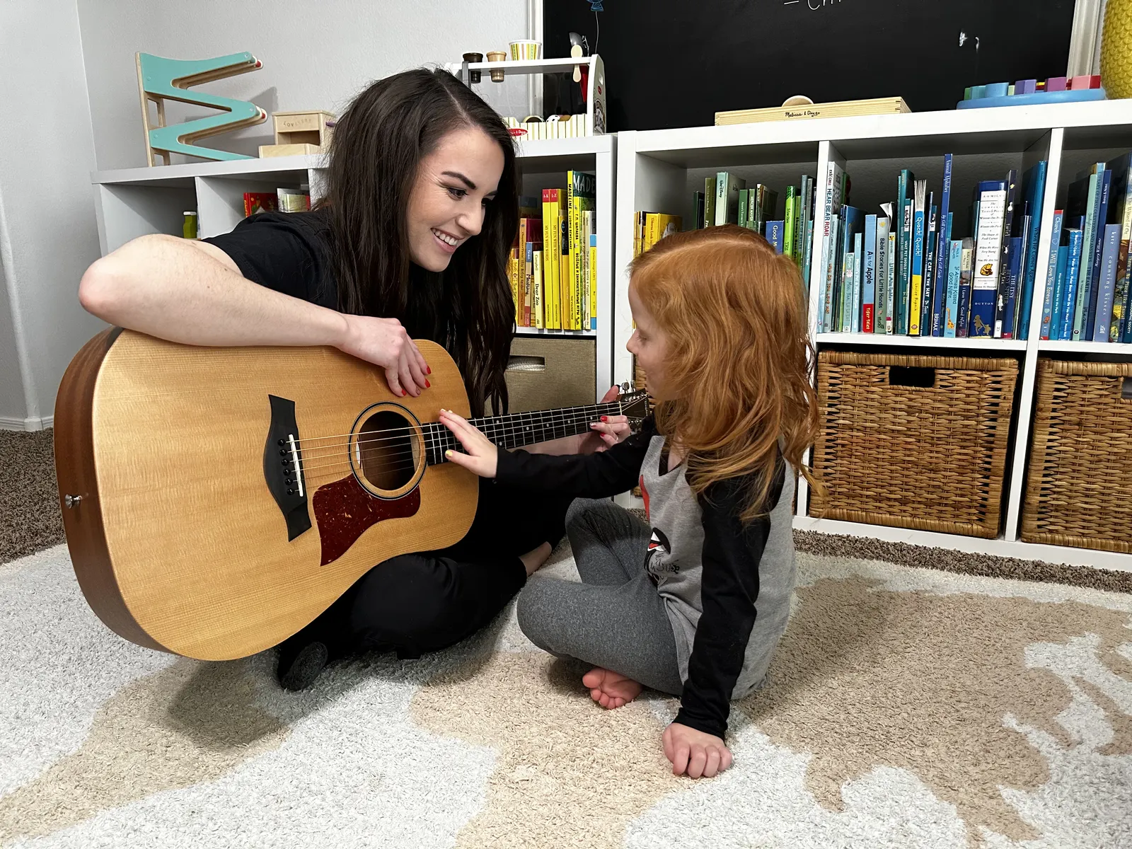 A music therapist and a child sharing an acoustic guitar during a music therapy activity